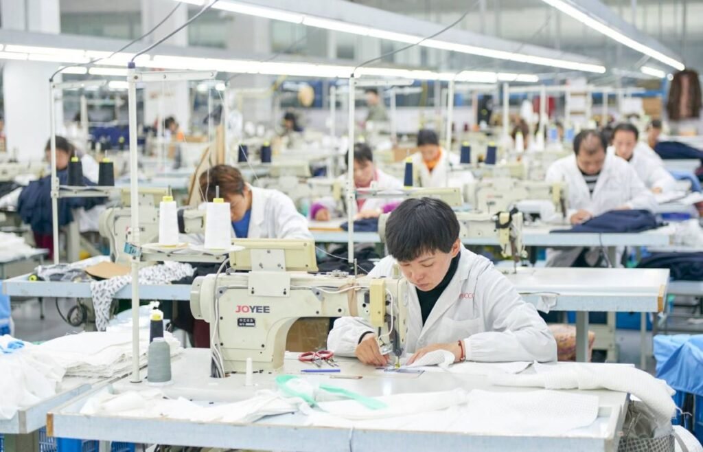 Skilled worker operating sewing machine in a custom clothing manufacturer in China producing garments for global fashion brands